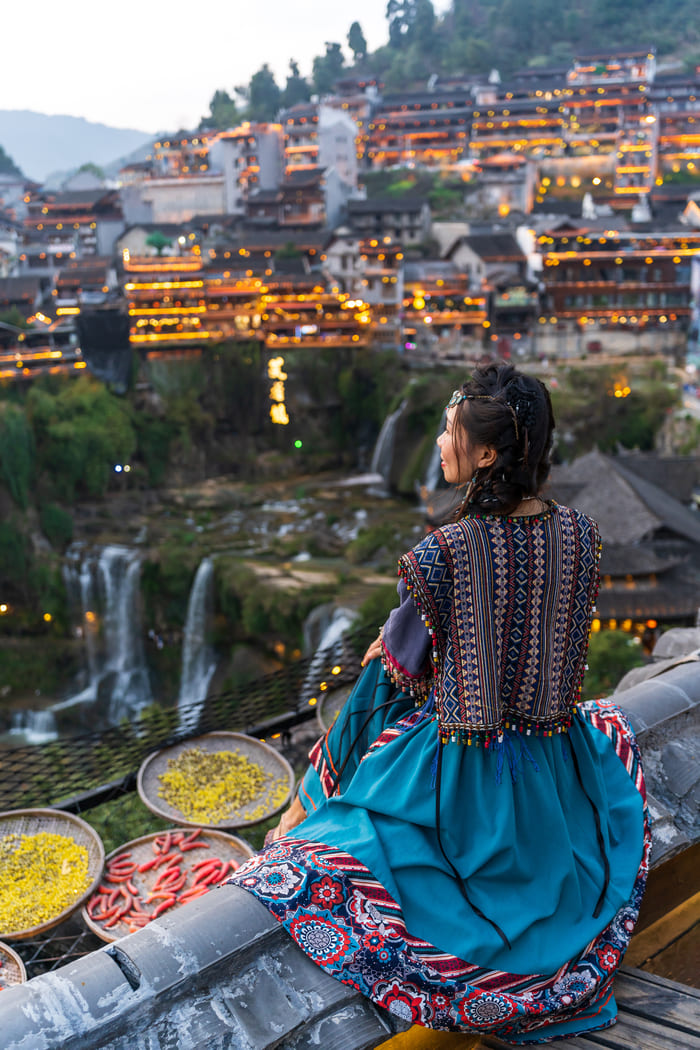 una dama esta sentada observando el paisaje que tiene frente a ella en un pueblo de china
